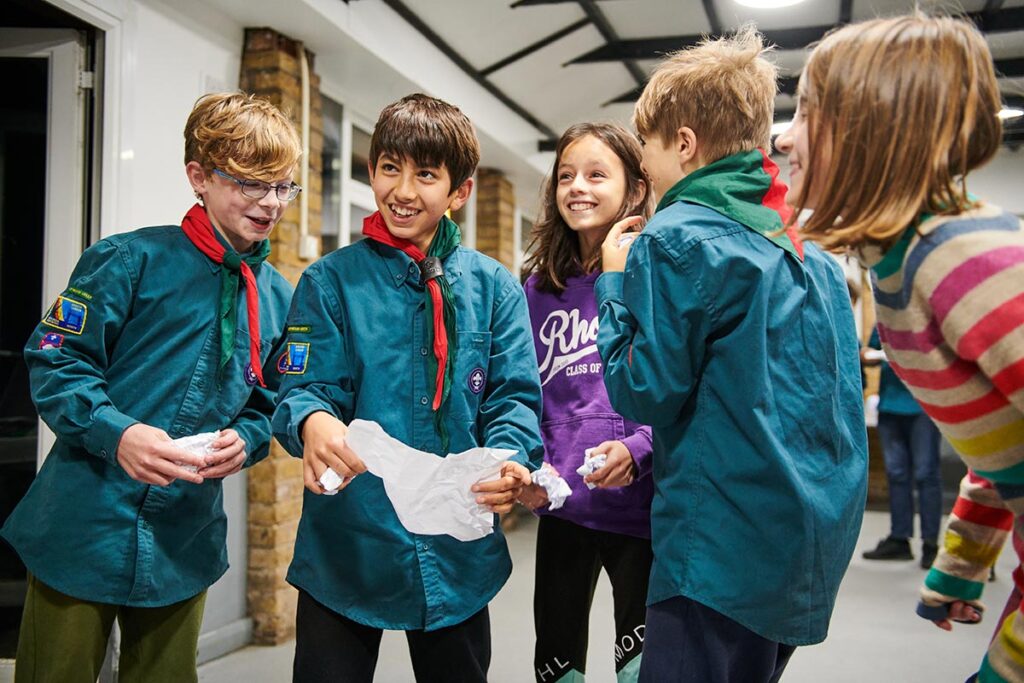 Young people crowding around as a scout reads out an idea.